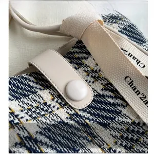 Close-up of blue and yellow tweed fabric with cream leather strap and buckle detail