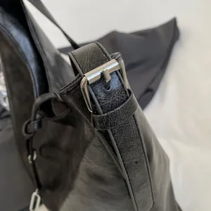 Detail of black vintage leather shoulder strap with silver adjustable buckle and buckle hole