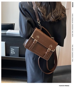 Detail view of brown vintage leather satchel with dual metal buckles and logo