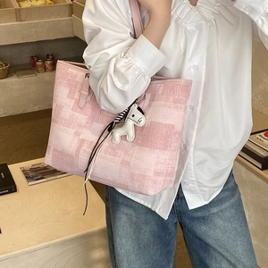 Detailed view of pink geometric tote bag with white horse pendant worn by a model