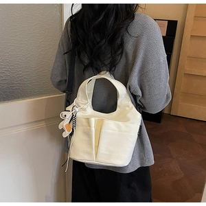 Dettaglio della borsa tote in tela bianca con tasche anteriori e ciondolo a cucciolo