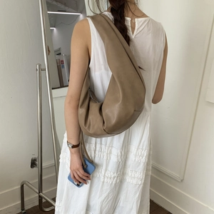 Detail view of earthy brown soft leather hobo bag with natural textured finish on model