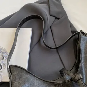 Detail view of black vintage textured leather shoulder bag with metallic buckle and strap