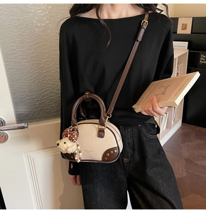 Detail of vintage beige shoulder bag with brown leather accents and bear charm