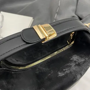 Close-up of black textured PU leather handbag with gold metal lock and zipper closure