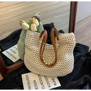 Close-up of woven straw tote bag featuring leather handles and pearl embellishments