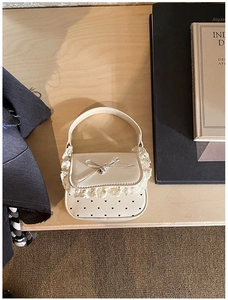 Detail of cream mini handbag with lace edges and heart-shaped cutout pattern