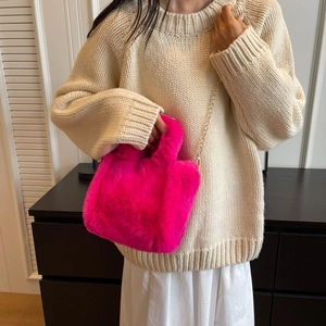 Détail du sac seau en fausse fourrure rose vif avec chaîne dorée sur pull en maille