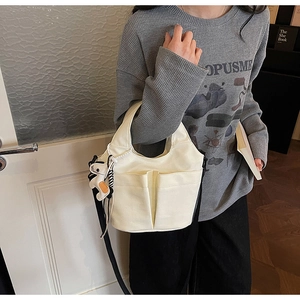 Vista dettagliata della borsa tote in tela bianco sporco con tasche e tracolla nera