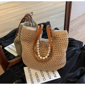 Detail of hand-woven straw tote with elegant pearl strap and brown leather handles