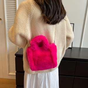 Détail du sac seau en peluche rose vif avec chaîne dorée sur une tenue neutre