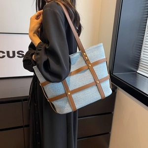 Detailed shot of denim patchwork tote bag with brown leather straps and metal rivets