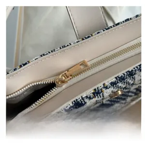 Detail of golden metal zipper and tweed texture on a stylish beige canvas tote bag