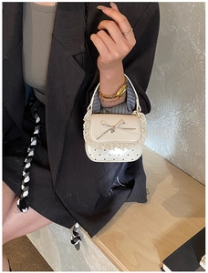 Close-up of cream mini handbag with lace trim, silver bow, and heart pattern accents