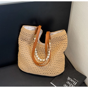 Detail of hand-woven straw tote with elegant pearl decoration and leather shoulder straps