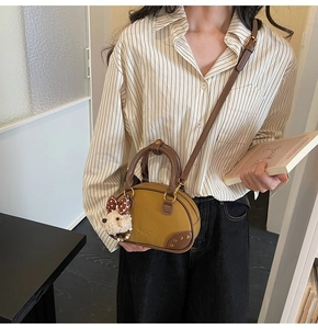 Detail of retro small khaki and brown crossbody bag with cute plush puppy charm on the side