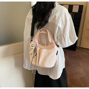 Dettaglio della borsa tote rosa chiaro con tasche frontali e tracolla nera rimovibile