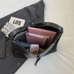 Spacious interior of a vintage dark grey leather tote bag holding two tablets and an umbrella