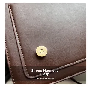 Detail of a strong golden magnetic buckle on dark brown leather with stitching