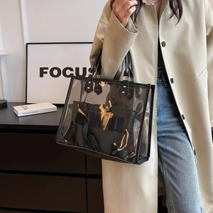 Transparent PVC tote bag with black inner pouch and rivet straps on a trench coat model