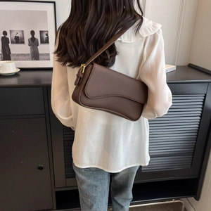 Dettaglio borsa a spalla in pelle marrone scuro con patta a onde e fibbia dorata elegante