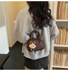 Detail of dark brown mini crossbody bag featuring golden rivets and cute puppy charm