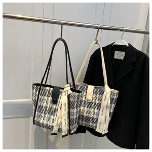 Detail of tweed tote bags with plaid patterns and leather handles in a fashion setup