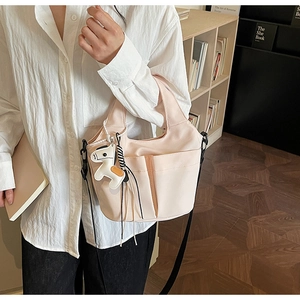 Dettaglio della borsa tote beige a pieghe con tasche laterali e ciondolo a cavallo bianco