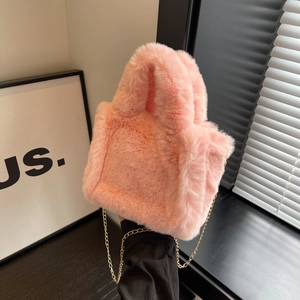 Gros plan d'un sac seau rose en fausse fourrure avec chaîne en métal doré élégante