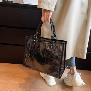 Detailed shot of transparent black PVC tote bag with leather handles and silver rivet accents