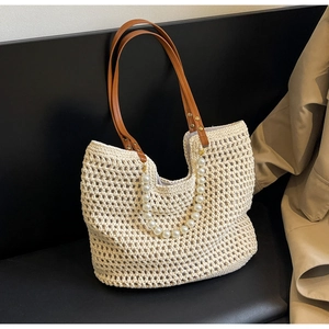 Detailed close-up of woven straw tote bag with pearl handle and brown leather straps
