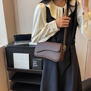 Borsa a tracolla marrone scuro motivo litchi con patta ondulata indossata da modella