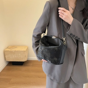Close-up of textured black PU leather square bag with golden hardware on a model
