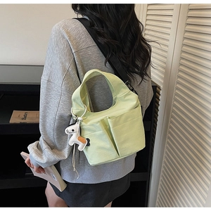 Vista dettagliata della borsa tote in tela verde chiaro con tasche e ciondolo pony