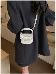 Close-up of white mini lace handbag featuring metal bow detail and heart pattern texture