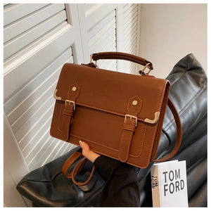 Detail view of the brown vintage leather handbag with buckle straps and textured matte finish