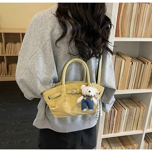 Détail du sac à main en cuir vert clair avec un charmant pendentif d'ours en peluche