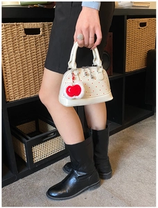 Close-up of a white polka dot mini shell bag with a red plush heart charm detail