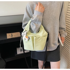 Dettaglio della borsa tote in tela verde pistacchio con tracolla e ciondolo a pony