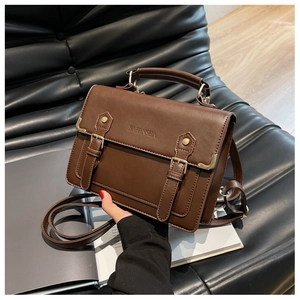 Detail of vintage brown leather satchel with metal buckle on a textured black surface