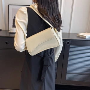 Dettaglio della borsa a tracolla in pelle beige con grana e fibbie dorate