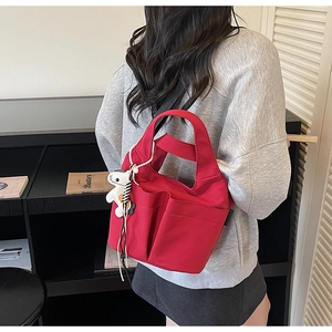 Vista posteriore di una borsa tote in tela rossa con tasche e ciondolo a cane