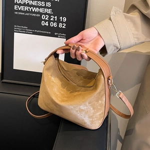 Detail of light brown PU leather crossbody bag with smooth handles and gold hardware
