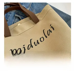 Detail of khaki canvas tote bag with brown straps and miduolai letter printing