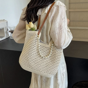 Chic beige straw tote bag with pearl handle and leather straps for beach holidays