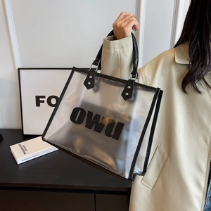 Detail of transparent PVC tote bag featuring black leather handles and metal hardware accents