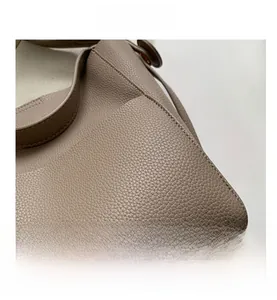 Vue macro de la texture en cuir litchi taupe et surpiqûres fines sur un sac seau chic