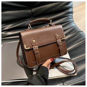 Detailed view of the dark brown vintage PU leather satchel bag on a black sofa