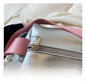 Detail of silver textured pillow bag with gold hardware and pink leather strap