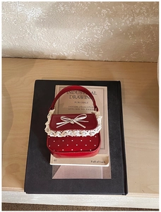 Detail of red mini handbag with white heart polka dots, lace edges and bow decoration